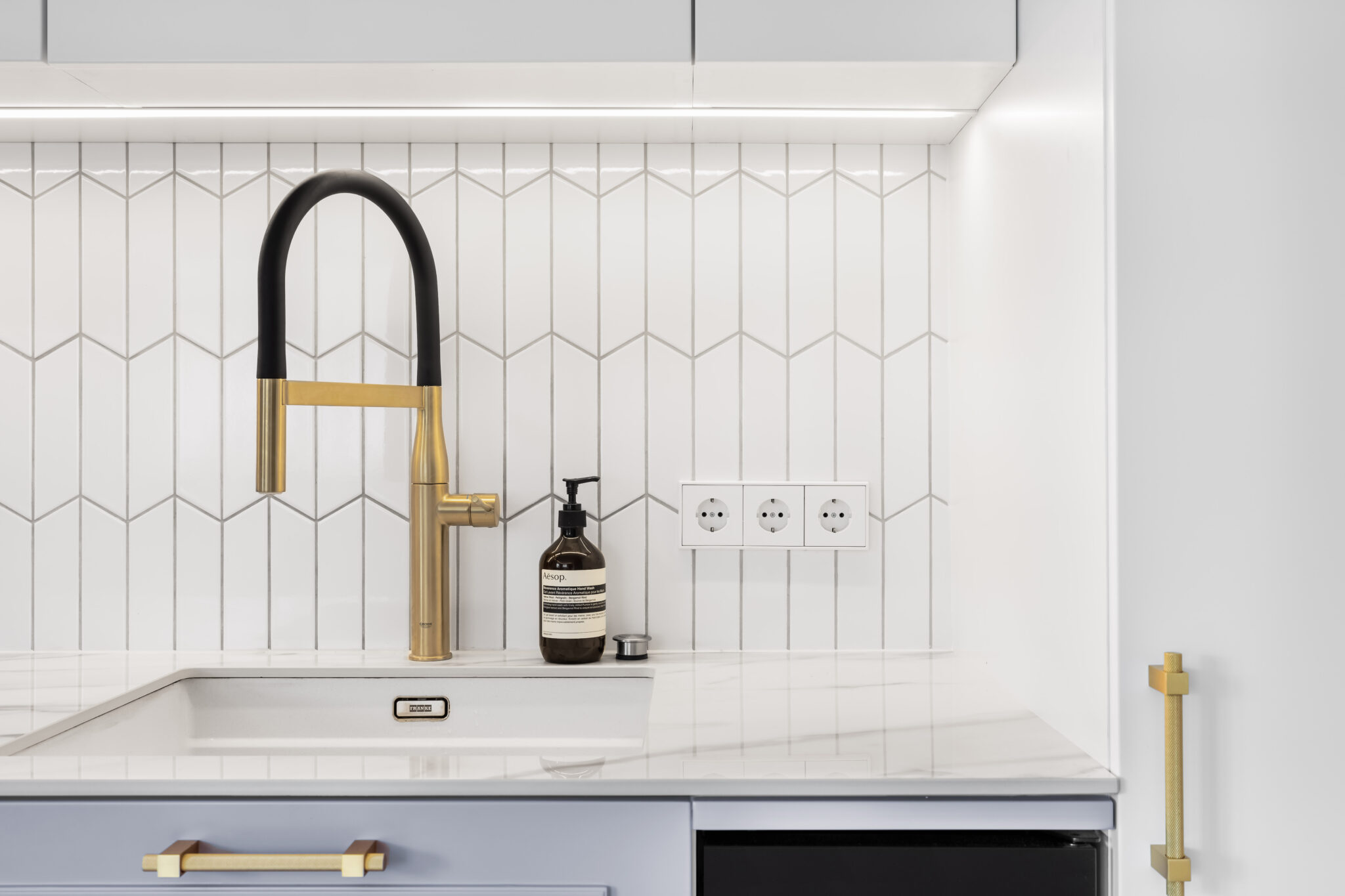 virtuvės baldai su Calacatta akmens stalviršiu ir auksiniu Grohe kranu